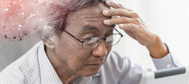 An Asian man holding his head, looking confused.