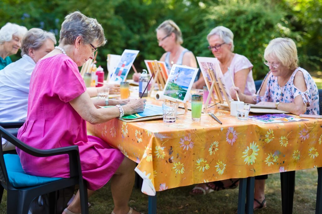 A group of older women taking a painting class.