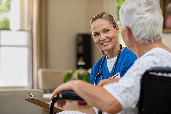 An image of a healthcare professional wearing a stethoscope smiling at an elderly person.