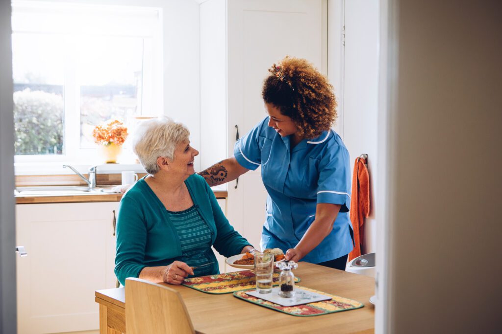 nurse greeting an elderly person who is sitting down